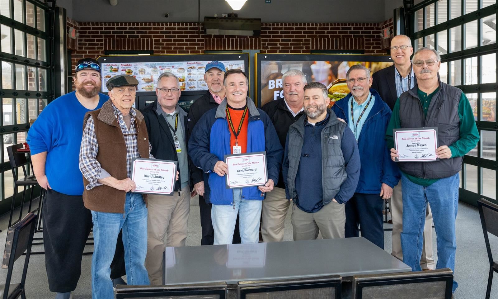 People smile while holding certificates